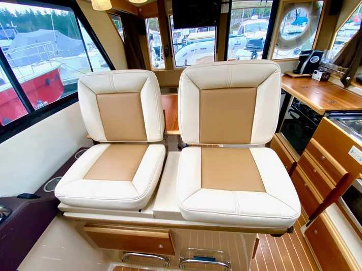 Sea Dreamer Yacht Photos Pics Interior of 2014 Cutwater 30 Sedan with beige and brown seating, wooden cabinetry, and large windows.