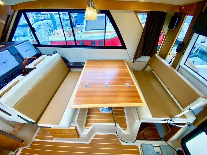 Sea Dreamer Yacht Photos Pics Interior of 2014 Cutwater 30 Sedan with wooden table and beige seating.