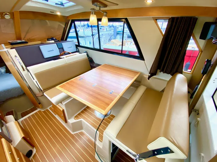 Sea Dreamer Yacht Photos Pics Interior of 2014 Cutwater 30 Sedan with wood table, beige seating, and large windows.
