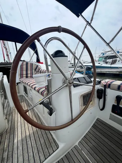 Miss Charlotte Yacht Photos Pics 2007 Jeanneau Sun Odyssey 39i sailboat cockpit with wooden steering wheel and striped seating.