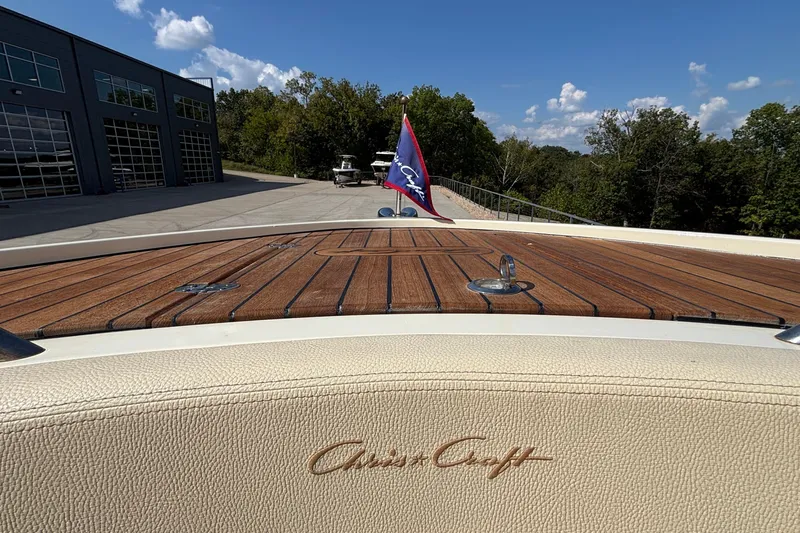  Yacht Photos Pics 2021 Chris-Craft Calypso 35 boat with wooden deck and flag, parked near a building.