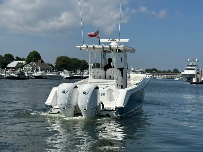  Yacht Photos Pics 2023 Edgewater 285CC boat with dual engines cruising in a marina under a clear sky.