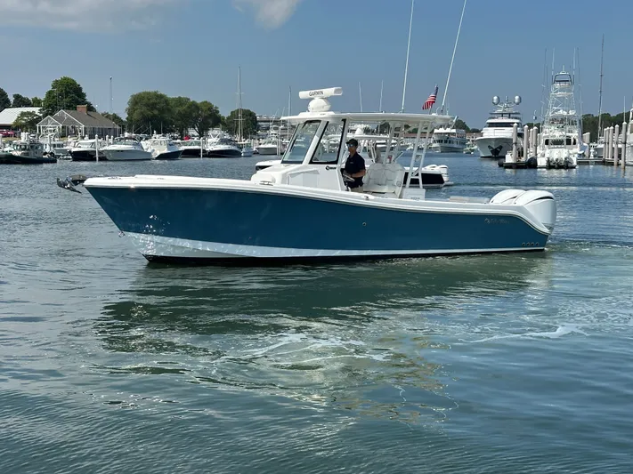  Yacht Photos Pics 2023 Edgewater 285CC boat cruising in a marina with multiple yachts in the background.