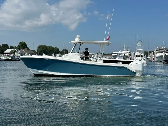 Yacht Photos Pics 2023 Edgewater 285CC boat cruising in a marina under a clear blue sky.