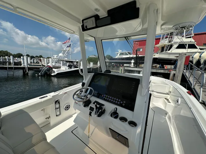 Yacht Photos Pics Interior view of 2023 Edgewater 285CC boat at a marina, featuring a modern control panel.