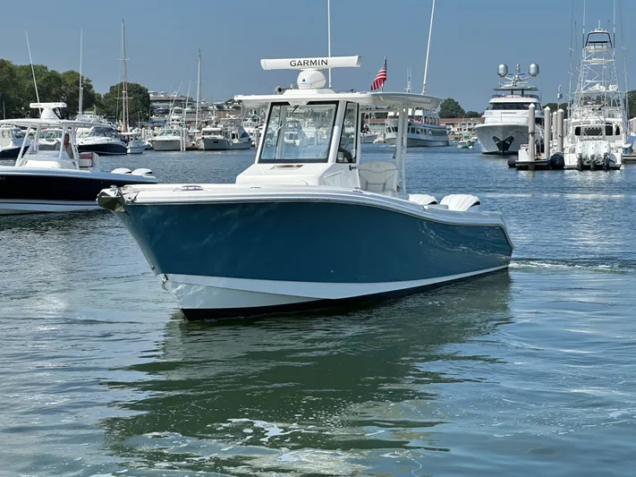  Yacht Photos Pics 2023 Edgewater 285CC boat on calm water, surrounded by other vessels in a marina.