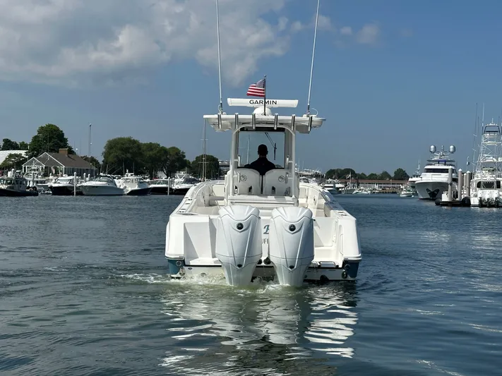  Yacht Photos Pics 2023 Edgewater 285CC boat cruising in a marina with clear skies.