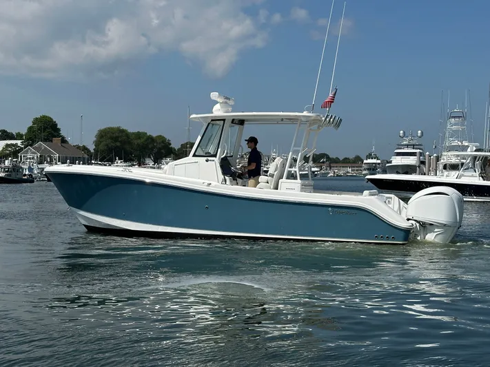  Yacht Photos Pics 2023 Edgewater 285CC boat cruising in a marina under a partly cloudy sky.