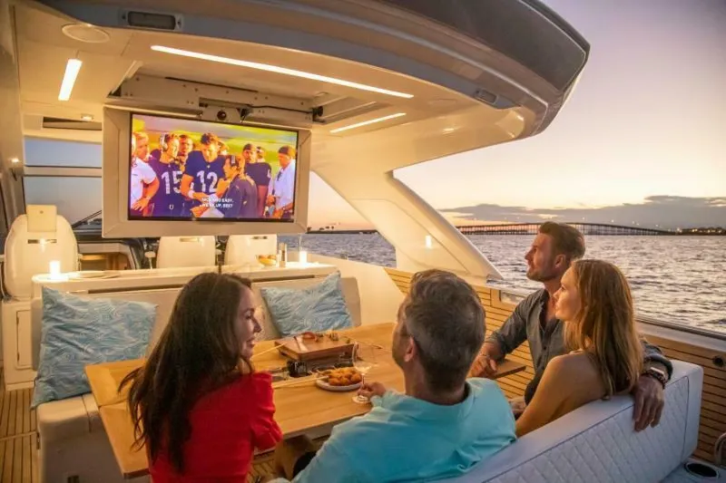  Yacht Photos Pics 2024 Jeanneau DB43 yacht with people watching TV at sunset on the water.