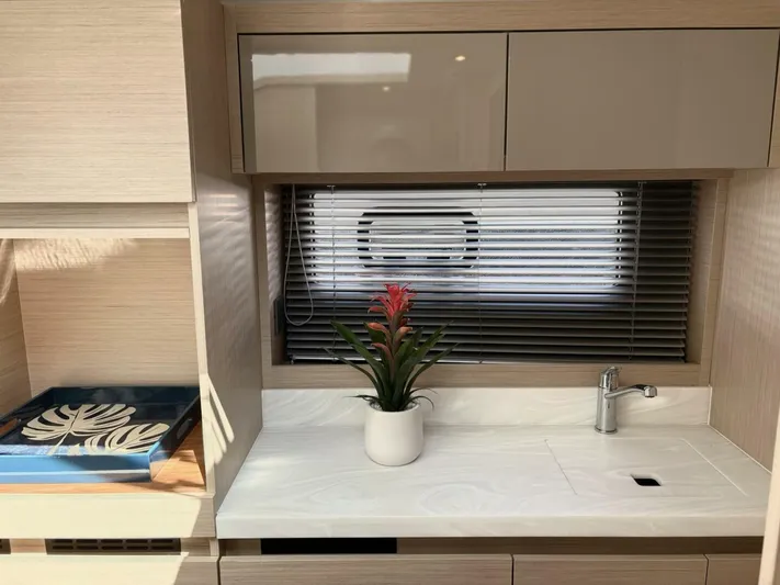  Yacht Photos Pics Modern kitchen area in 2024 Jeanneau DB43 yacht with sleek cabinetry and potted plant.