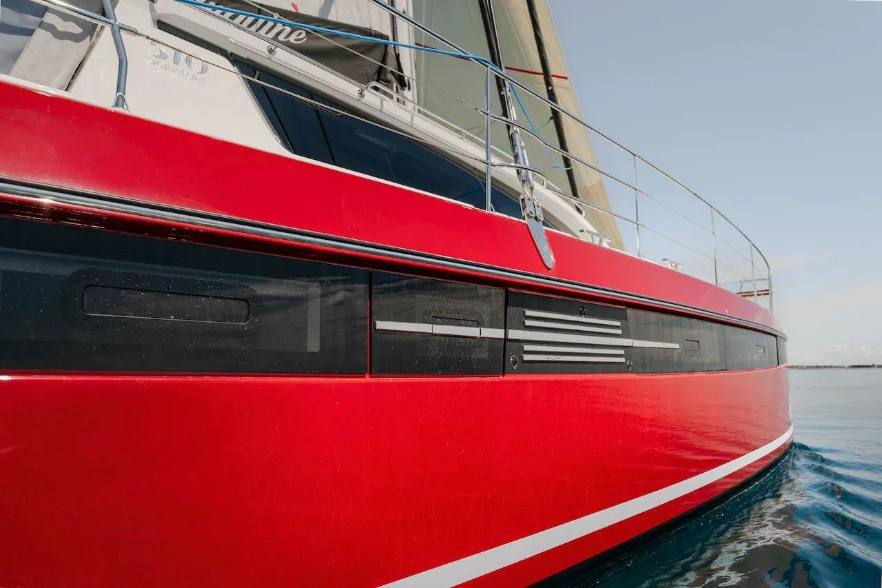 Red Privilege Signature 510 sailboat, 2025 model, on calm water.