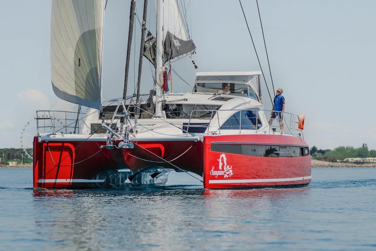 Red Privilege Signature 510 catamaran sailing on calm waters, year 2025.