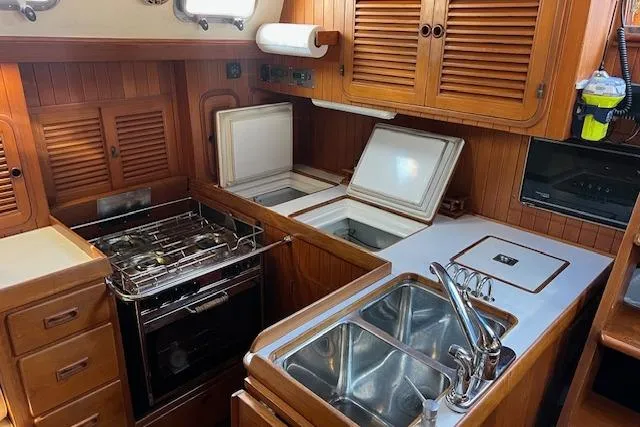 Southern Cross Yacht Photos Pics 1987 Tayana Vancouver 42 yacht kitchen with stove, sink, and wooden cabinetry.