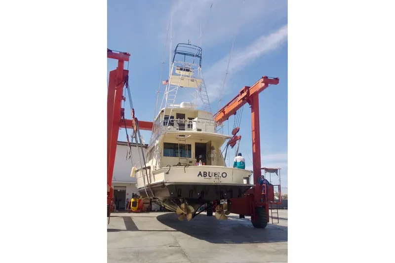Abuelo Yacht Photos Pics 1989 HATTERES Convertible yacht on lift, showcasing its structure and propellers.