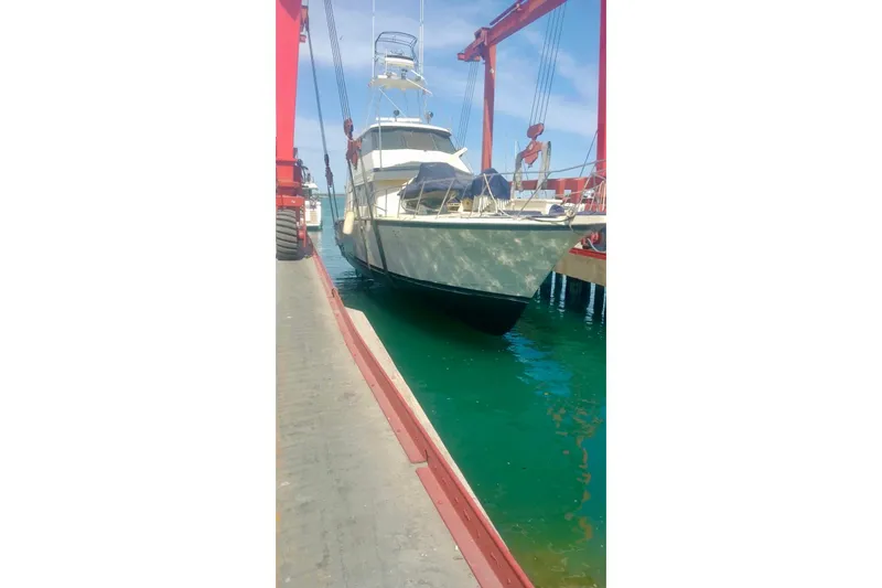 Abuelo Yacht Photos Pics 1989 HATTERES Convertible boat being lifted at a marina with clear blue water.
