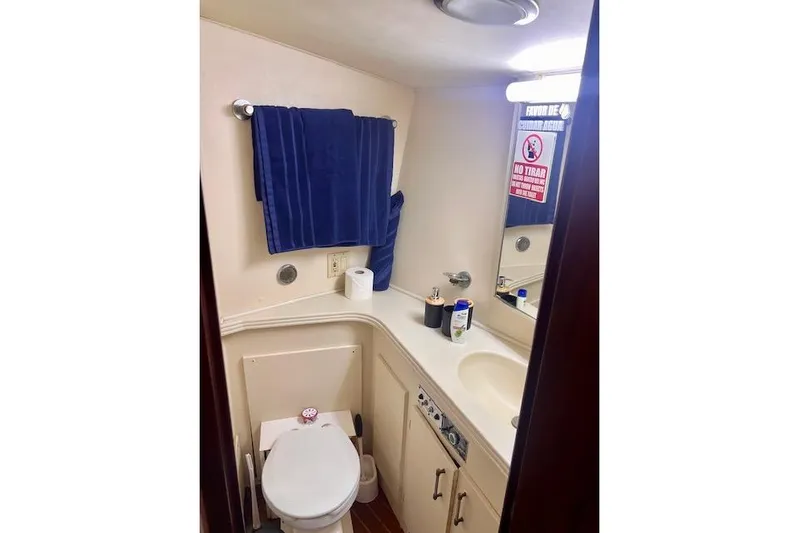 Abuelo Yacht Photos Pics Compact bathroom in a 1989 HATTERES Convertible boat, featuring a toilet, sink, and blue towel.