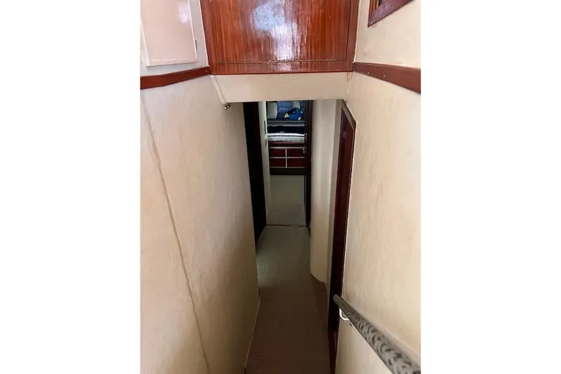 Abuelo Yacht Photos Pics Narrow hallway inside 1989 HATTERES Convertible boat, featuring wooden accents and carpeted floor.