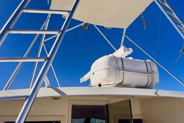 Abuelo Yacht Photos Pics 1989 HATTERES Convertible boat with life raft on deck under clear blue sky.