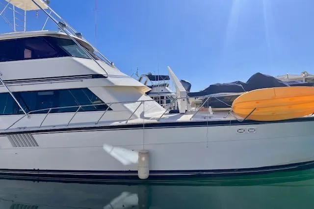 Abuelo Yacht Photos Pics 1989 HATTERES Convertible yacht docked with a kayak on deck under clear blue sky.