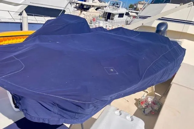 Abuelo Yacht Photos Pics 1989 HATTERES Convertible yacht covered with a blue tarp at a marina.