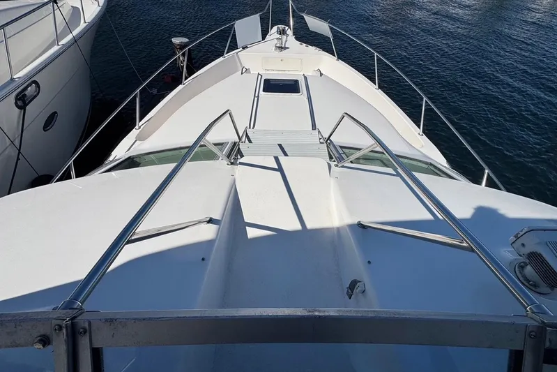 Pearl Yacht Photos Pics 1994 Sea Ray 440 Express Bridge yacht deck with railing, docked on calm water.