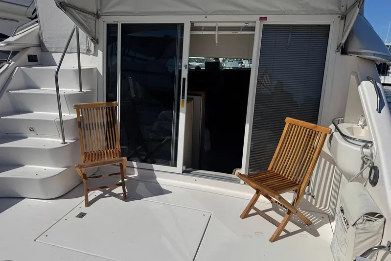 Pearl Yacht Photos Pics 1994 Sea Ray 440 Express Bridge deck with wooden chairs and sliding glass door.