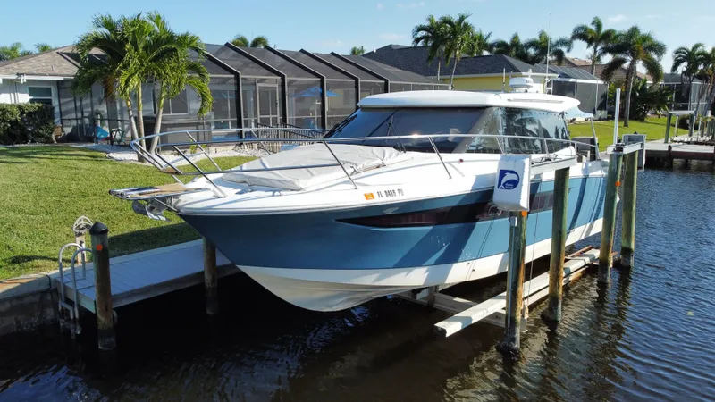 Funkytown 2 Yacht Photos Pics 2014 Jeanneau NC 11 boat docked by a waterfront home with palm trees.