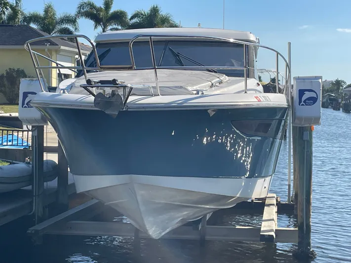 Funkytown 2 Yacht Photos Pics 2014 Jeanneau NC 11 boat docked on a lift, surrounded by palm trees.