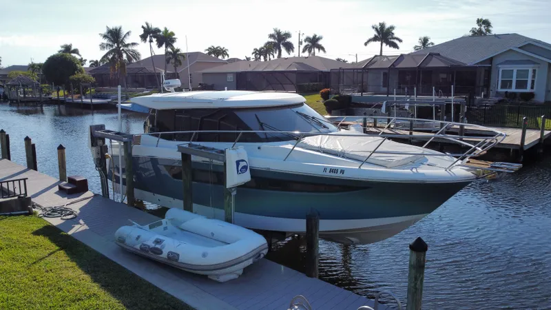 Funkytown 2 Yacht Photos Pics 2014 Jeanneau NC 11 docked by waterfront homes with palm trees.