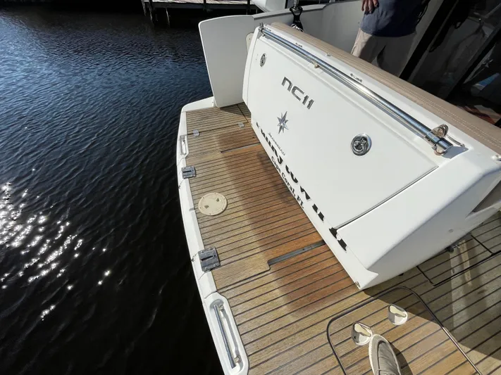 Funkytown 2 Yacht Photos Pics 2014 Jeanneau NC 11 boat stern with teak deck, docked on calm water.