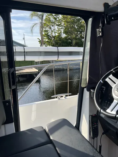 Funkytown 2 Yacht Photos Pics Interior view of 2014 Jeanneau NC 11 boat, showing steering wheel and dockside scenery.
