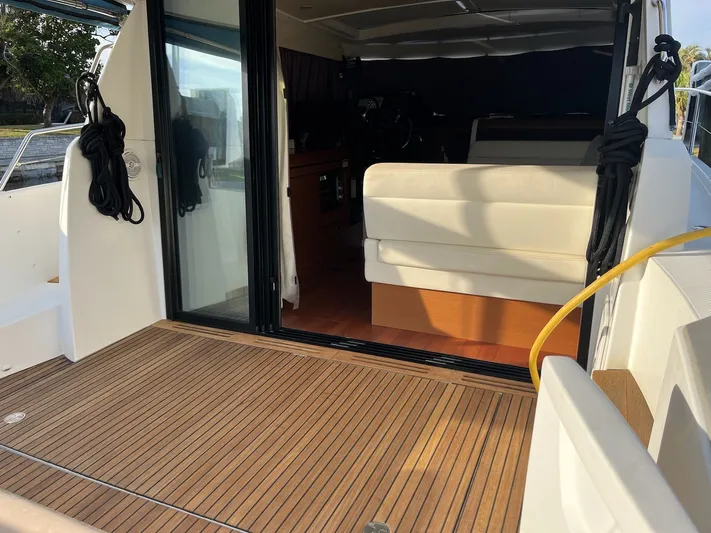 Funkytown 2 Yacht Photos Pics 2014 Jeanneau NC 11 boat interior with sliding glass door and wooden deck.