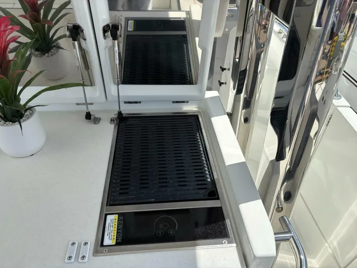 Jeanneau Yacht Photos Pics Outdoor grill on 2024 Jeanneau 12.5 Walk boat, with sleek design and potted plants.