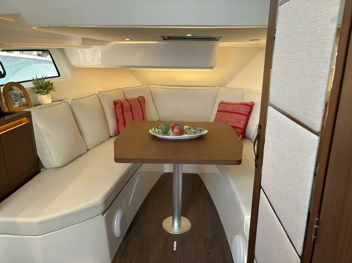 Jeanneau Yacht Photos Pics 2024 Jeanneau 12.5 Walk interior with cozy seating and wooden table.