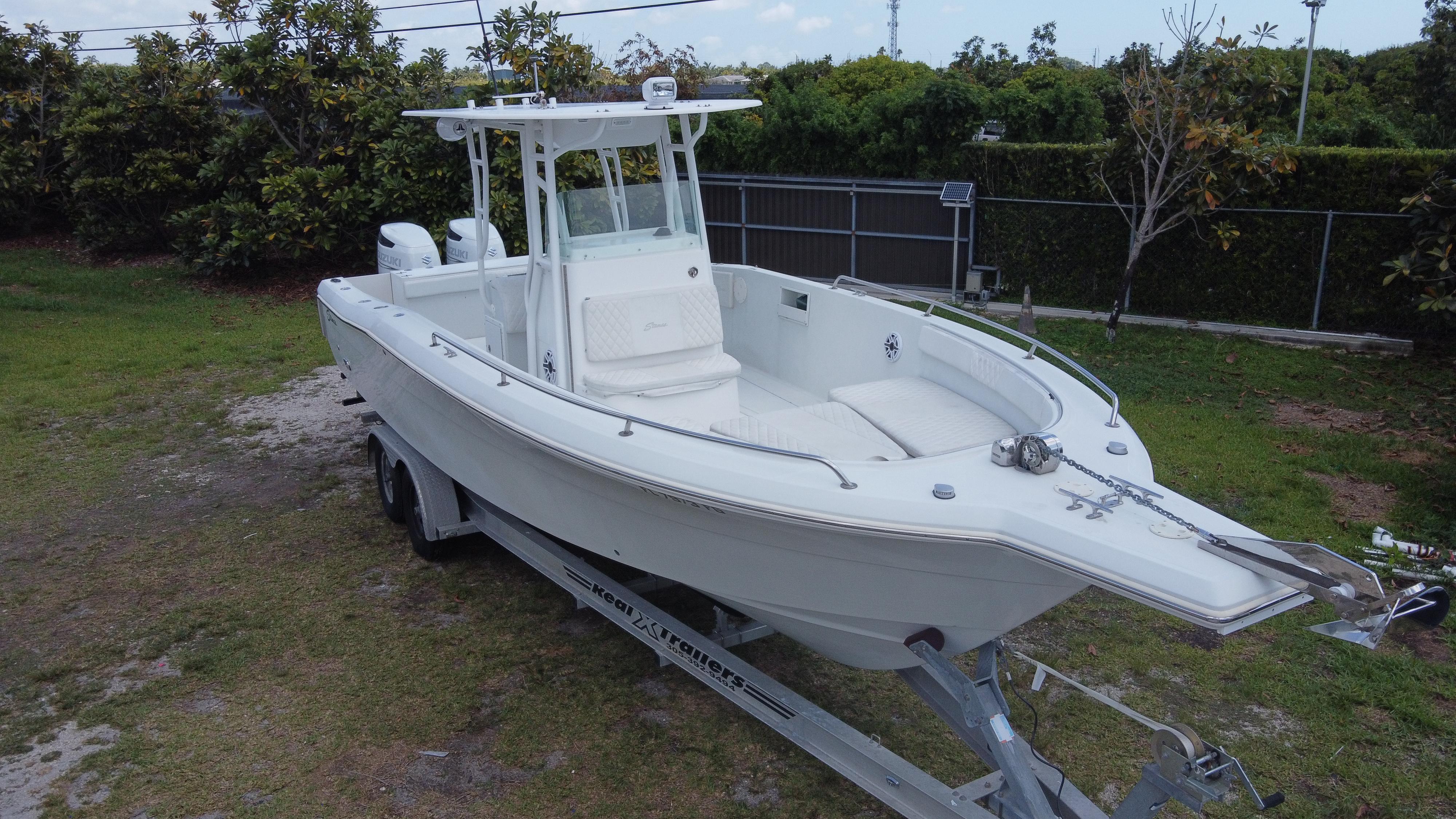 1997 Stamas 290 Tarpon boat on trailer, parked on grass, ready for transport.