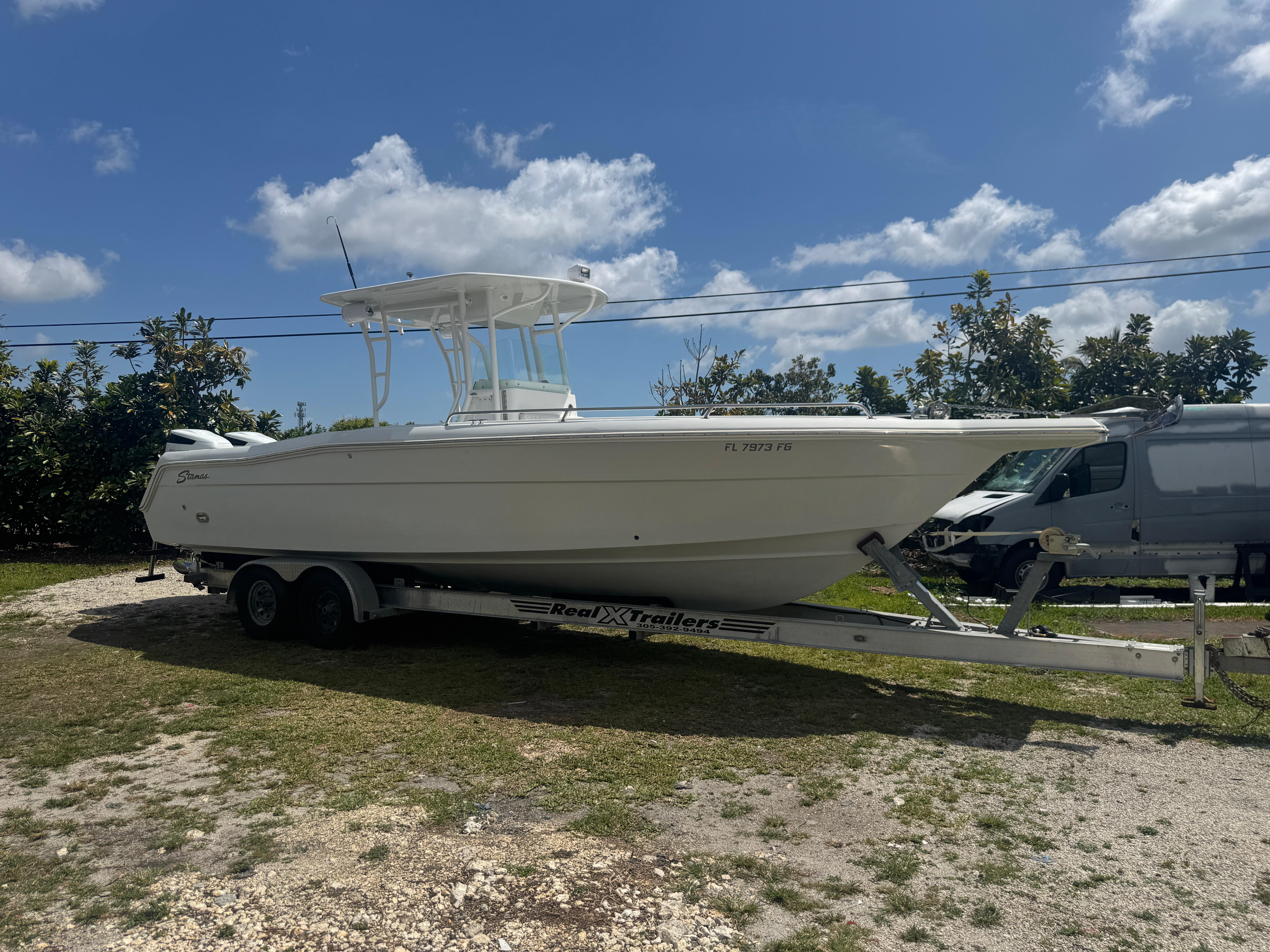 1997 Stamas 290 Tarpon boat on trailer under clear blue sky.