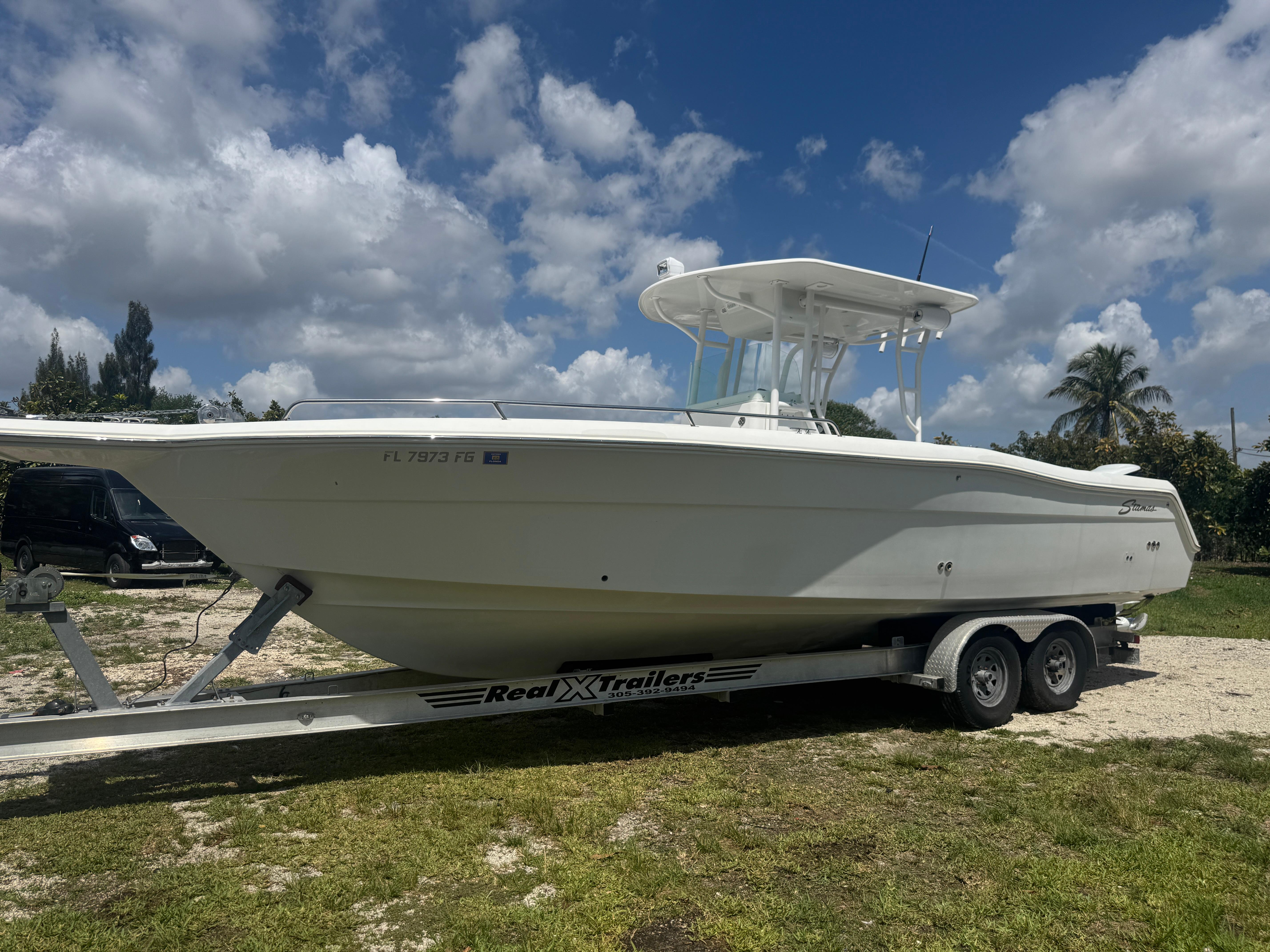 1997 Stamas 290 Tarpon boat on trailer under a partly cloudy sky.