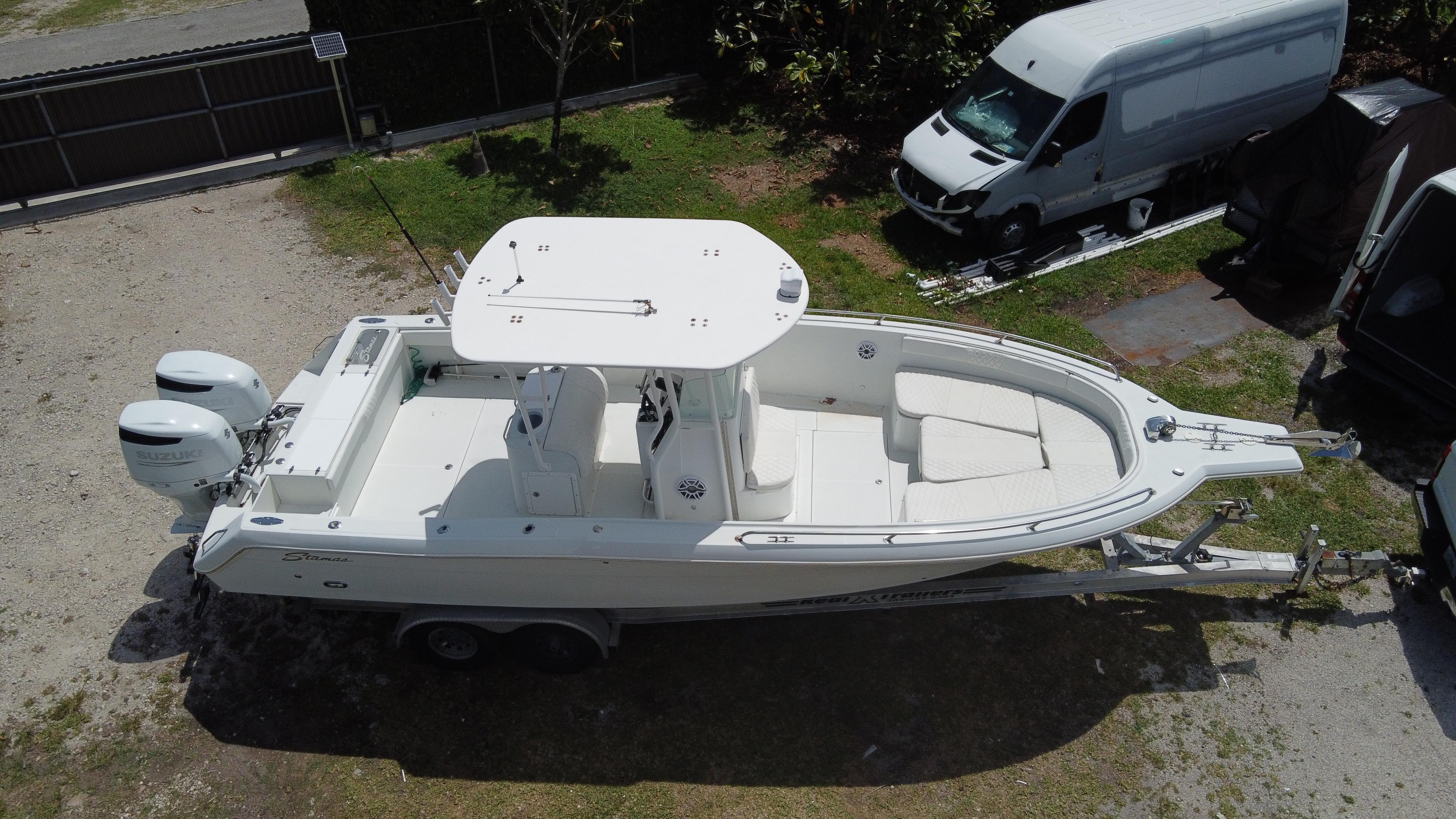 1997 Stamas 290 Tarpon boat on trailer, aerial view, parked near a white van.