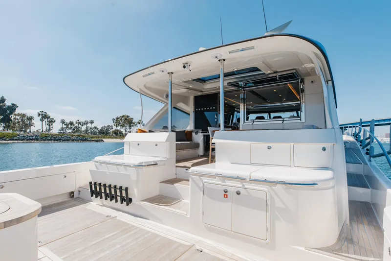 Hermosa Yacht Photos Pics 2022 Riviera 645 SUV yacht with spacious deck and modern design, docked by the water.