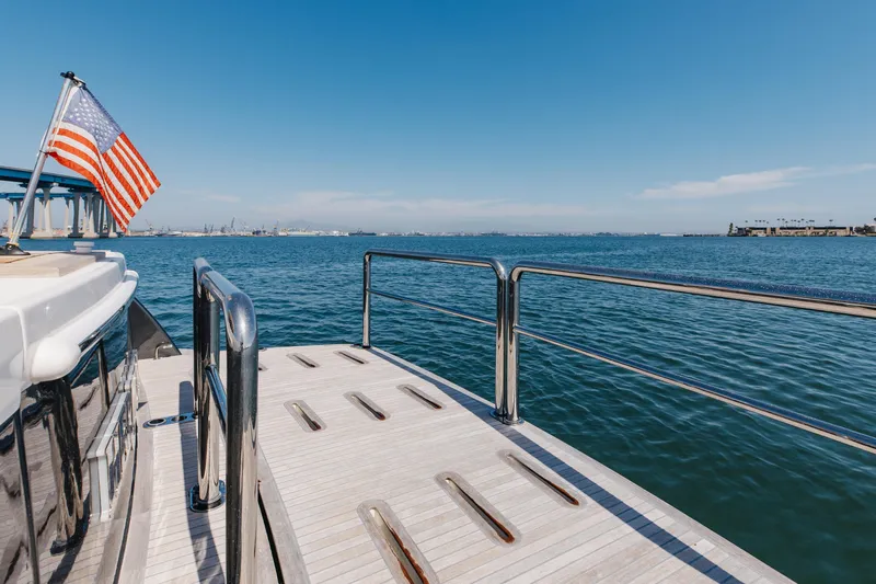 Hermosa Yacht Photos Pics 2022 Riviera 645 SUV yacht deck with American flag, overlooking calm ocean waters.