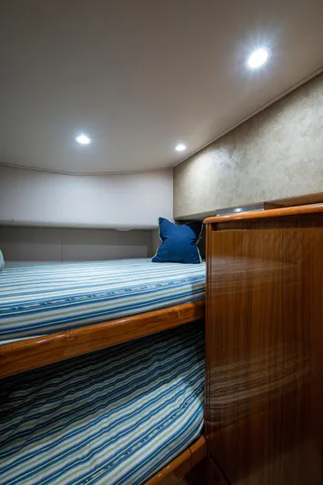 Blind Date Yacht Photos Pics 2016 Viking 46 Convertible cabin interior with striped bedding and wooden cabinetry.