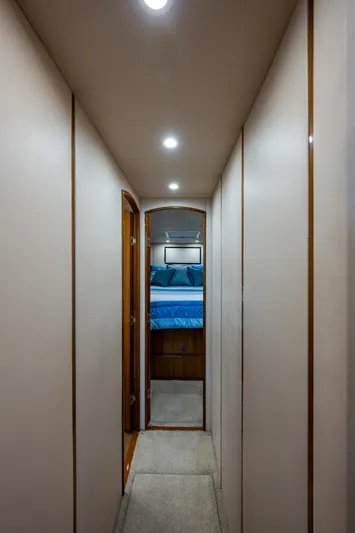 Blind Date Yacht Photos Pics Hallway inside 2016 Viking 46 Convertible yacht, leading to a bedroom with blue bedding.