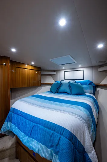 Blind Date Yacht Photos Pics 2016 Viking 46 Convertible yacht bedroom with blue bedding and wooden cabinets.
