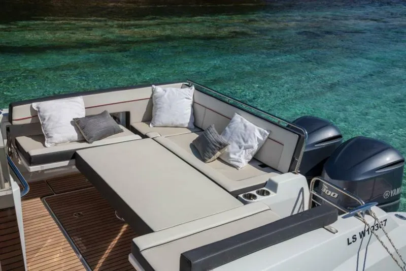  Yacht Photos Pics 2024 Jeanneau 10.5 WALK boat with cushioned seating, pillows, and twin Yamaha engines.