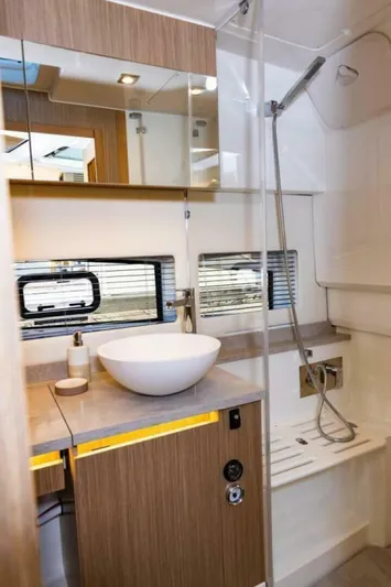  Yacht Photos Pics 2024 Jeanneau 10.5 WALK bathroom with modern sink, shower, and wooden cabinetry.