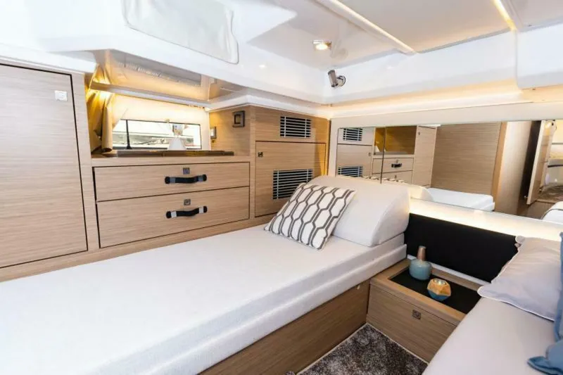  Yacht Photos Pics 2024 Jeanneau 10.5 WALK cabin interior with modern wood finish and cozy bedding.