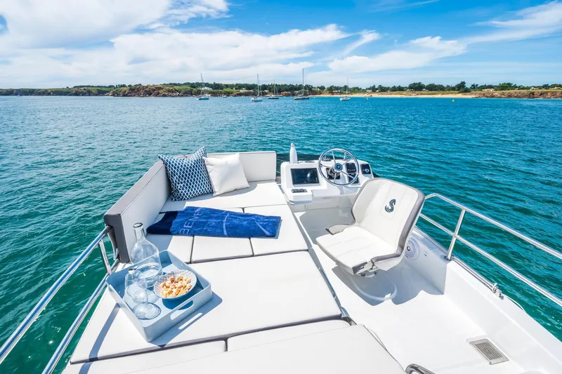  Yacht Photos Pics 2026 Beneteau Antares 11 yacht deck with seating, ocean view, and clear blue skies.