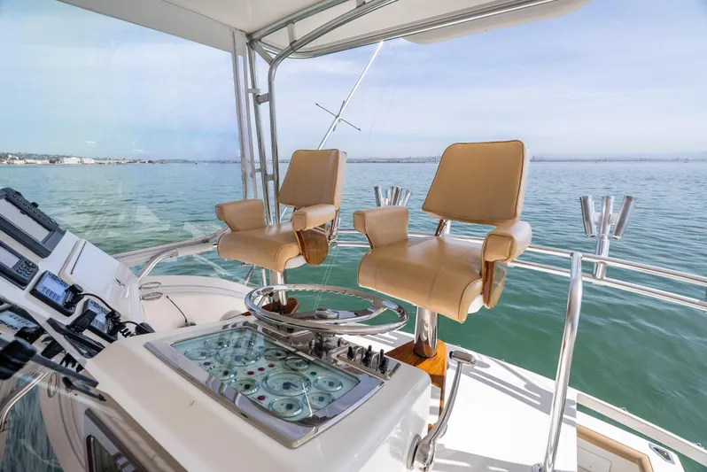 Dieguito Yacht Photos Pics Flybridge of 2004 Cabo 48, featuring dual captain chairs and control panel, overlooking serene waters.