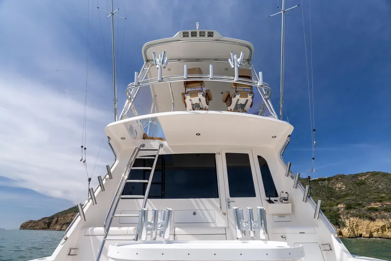 Dieguito Yacht Photos Pics 2004 Cabo 48 Flybridge yacht with sleek design, docked near rocky coastline under blue sky.