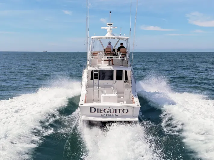 Dieguito Yacht Photos Pics 2004 Cabo 48 Flybridge yacht cruising on open sea, rear view.